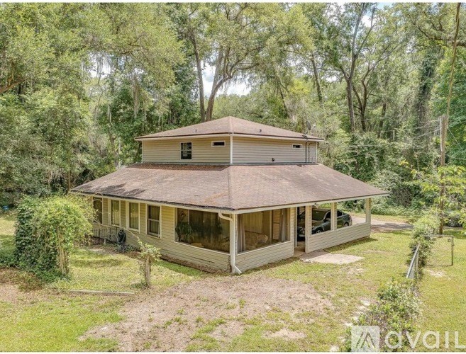 A house with a brown roof is surrounded by greenery.