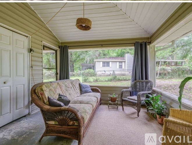 A sunroom with a wicker couch and a chair.