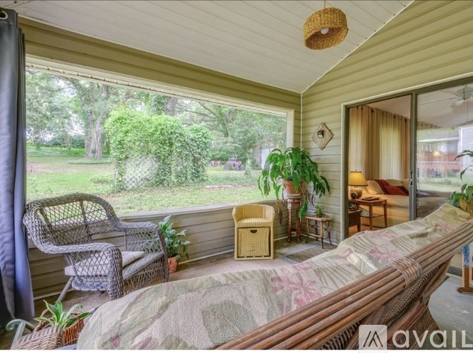 A sunroom with a couch, chair, and plants.