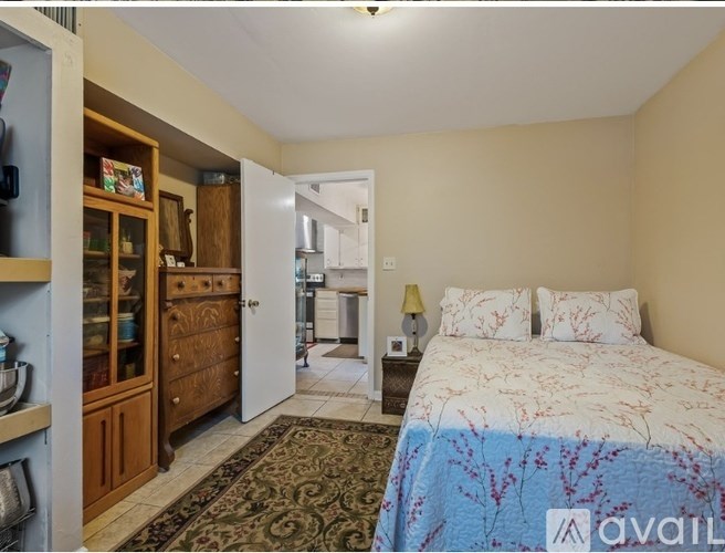 A bedroom with a bed, dresser, and a cabinet with glass doors.