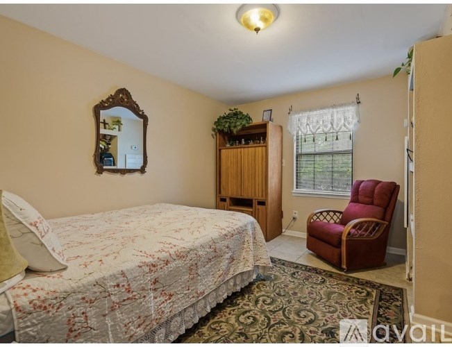 A bedroom with a bed, chair, and mirror.