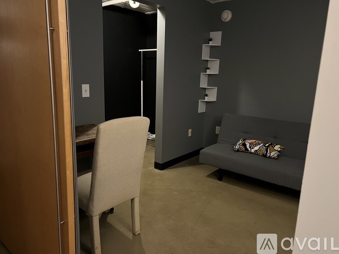 A room with a grey couch and a white chair.