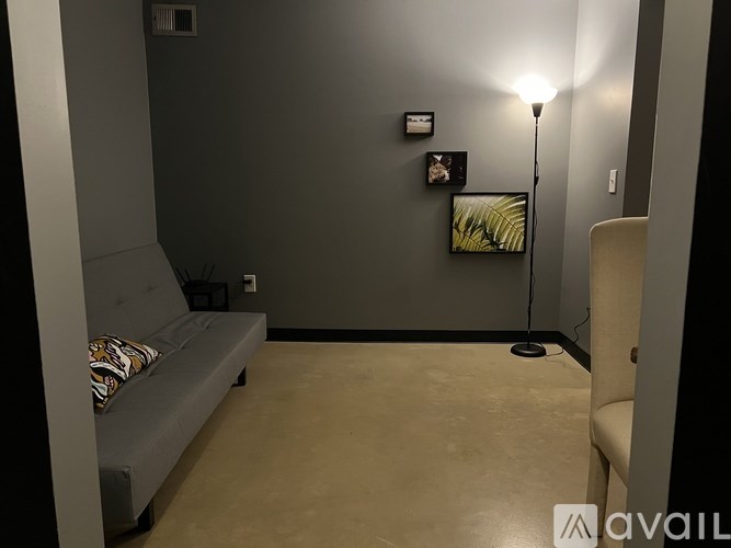 A room with a grey couch and a floor lamp.