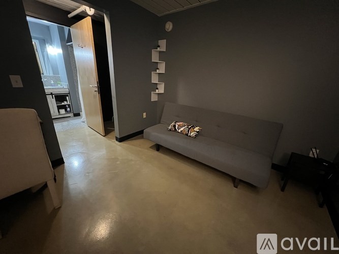 A living room with a grey couch and a black piano.