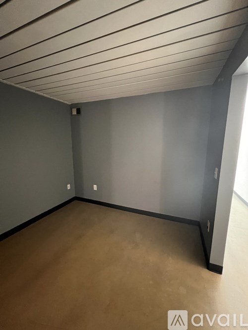 A room with a wooden floor and grey walls.