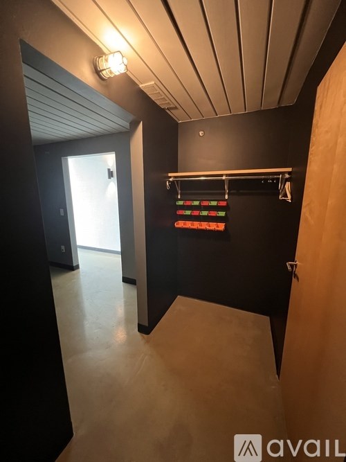 A hallway with a black wall and a wooden door.