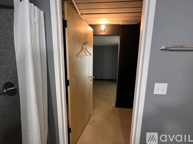 A hallway with a door on the left and a towel rack on the right.