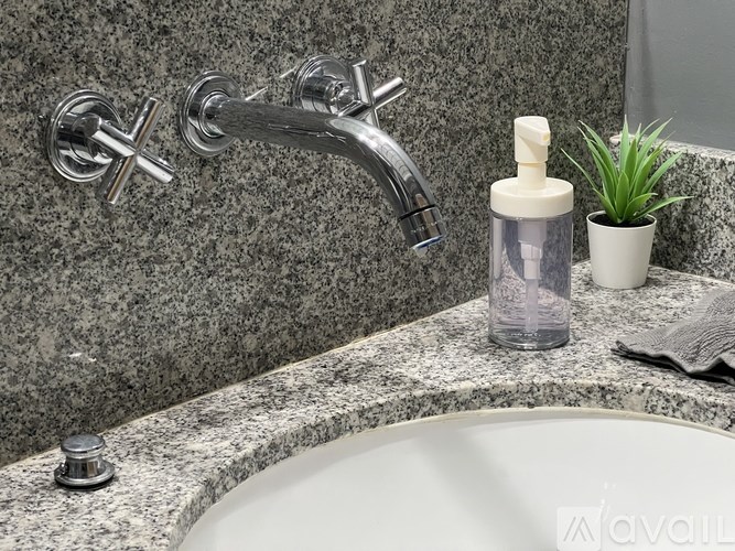 A bathroom sink with a white basin and a grey granite countertop.
