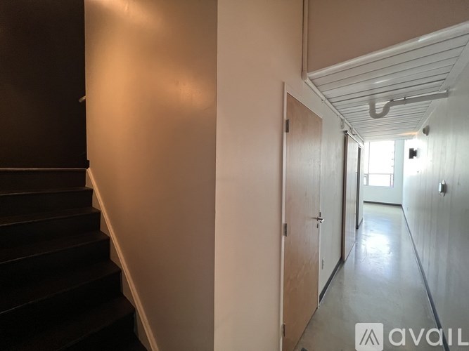 A long hallway with a staircase on the left and a door on the right.