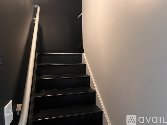 A staircase with a metal railing and black steps.