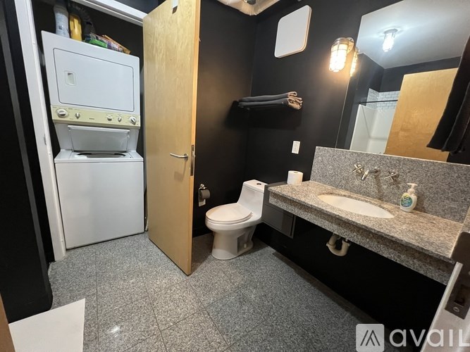A bathroom with a toilet, sink, and a small refrigerator.