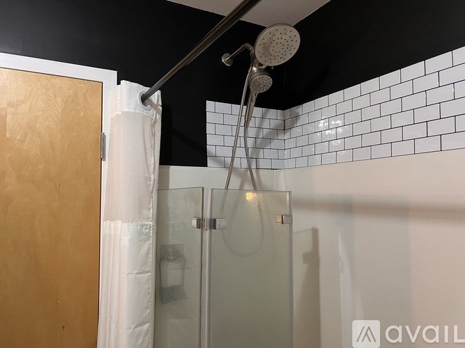 A shower area with a glass door and a brown door.
