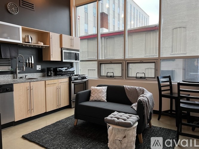 A kitchen with a black couch and a black chair.