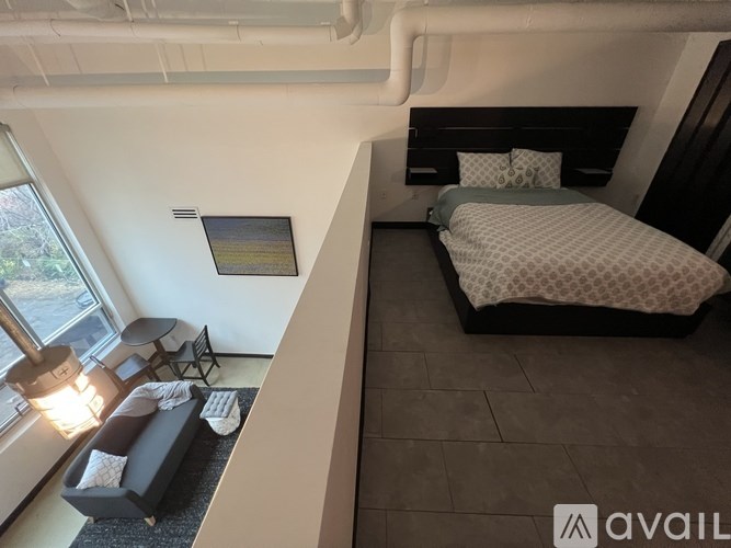 A bedroom with a bed, a couch, and a window with a view of trees.