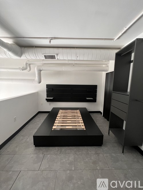 A modern bedroom with a bed in the center and a cabinet to the right.