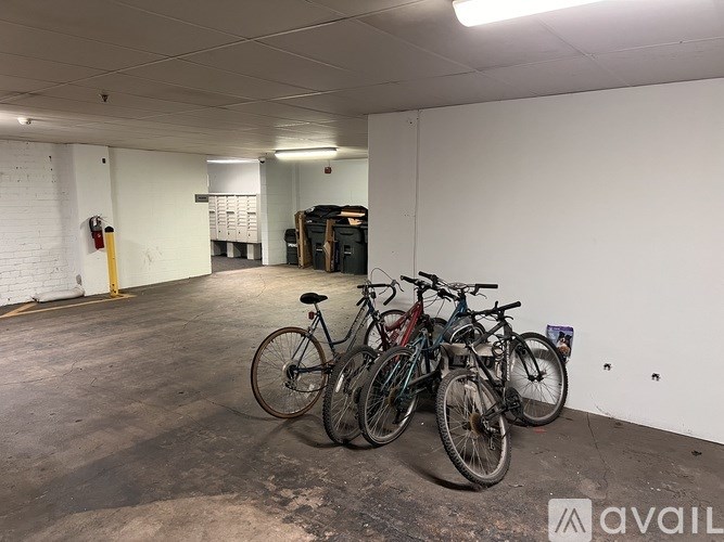 A room with a white wall and a fire extinguisher on the left side, and bicycles leaning against the wall.
