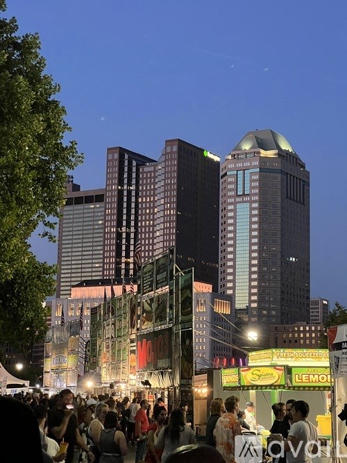 A crowd of people are gathered in front of a building with a lit up sign that says "LEMON".