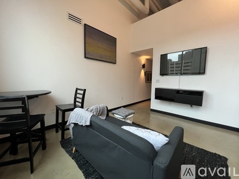 A living room with a grey couch, a black chair, and a painting on the wall.