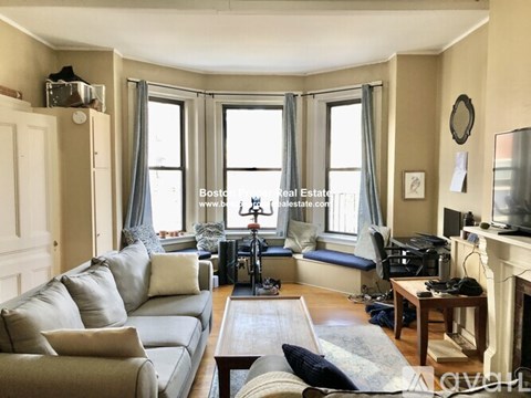 A living room with a grey couch and a fireplace.