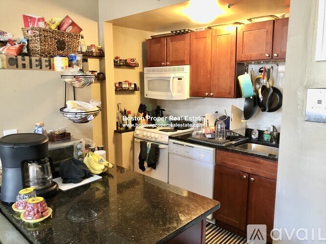 A kitchen with a black granite counter top and wooden cabinets.