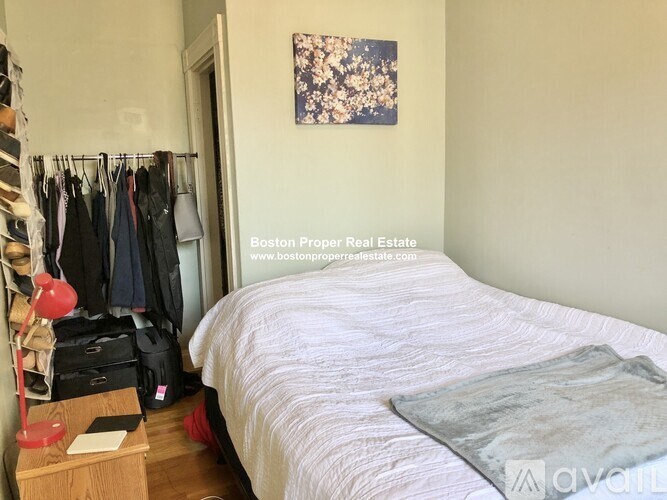 A bedroom with a bed, a nightstand, and a closet with clothes.