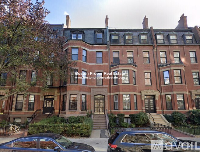 A large red brick building with a black car parked in front.