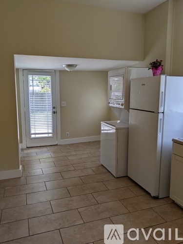 A kitchen with a white fridge and a door leading outside.