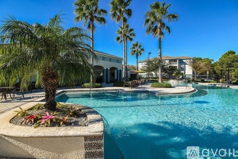 A pool surrounded by palm trees and a building in the background.