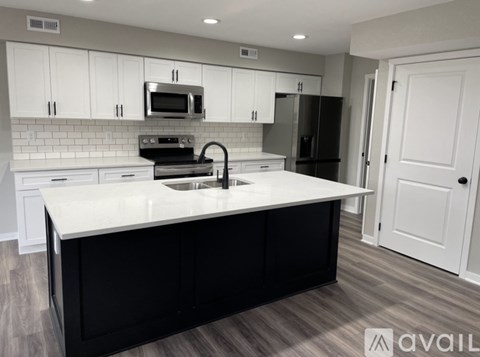 A kitchen with white cabinets and black appliances.