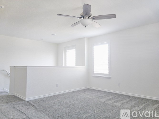 A spacious room with a fan and two windows.