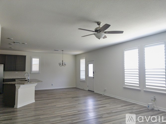 A spacious room with a kitchen area and a ceiling fan.