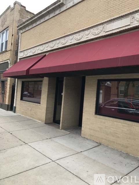 A building with a red awning and a car parked in front.