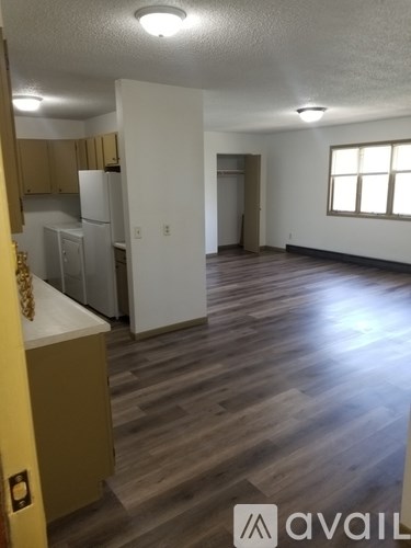 A kitchen area with a refrigerator and wooden floors.