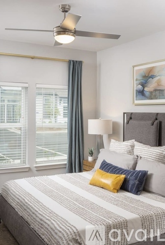 A bedroom with a bed, a ceiling fan, and a window with blinds.
