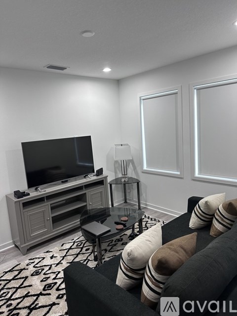 A living room with a black couch and a television.