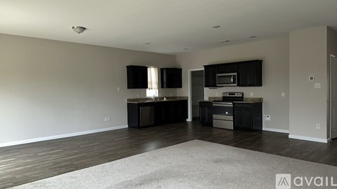 A spacious living room with a grey rug in the center.
