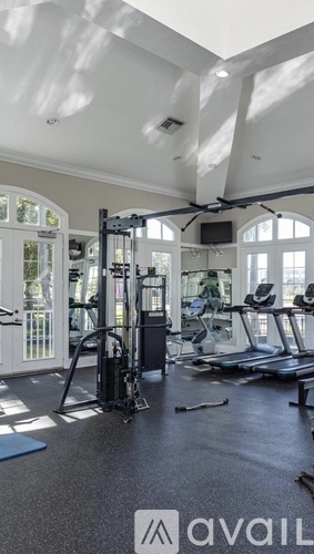 A gym with a variety of equipment including treadmills, weights, and a television.