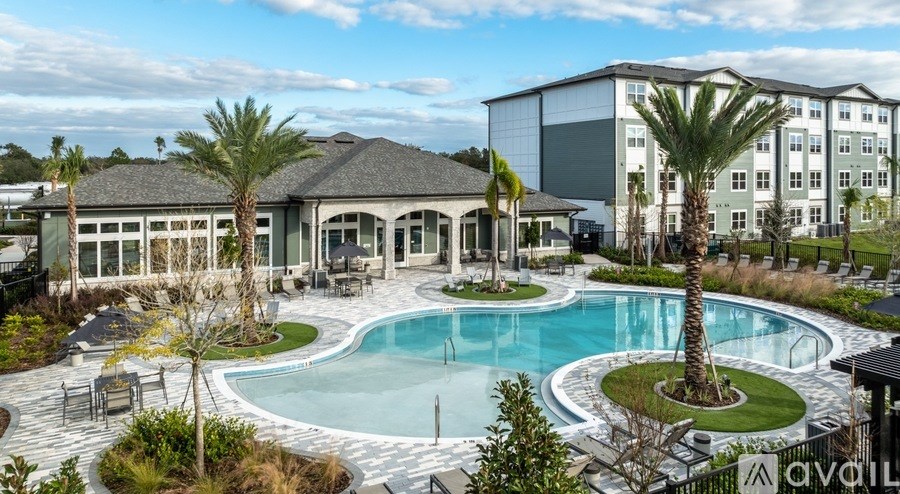 A large outdoor swimming pool surrounded by palm trees and lounge chairs.