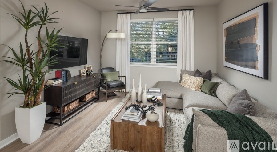 A living room with a large couch, a coffee table, and a flat-screen TV.