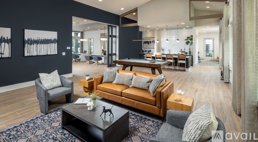 A modern living room with a dark blue rug and a wooden coffee table.