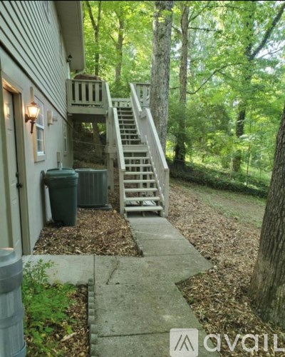 A house with a staircase leading to a deck in a wooded area.