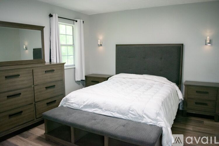 A bedroom with a large bed, a dresser, and a mirror.