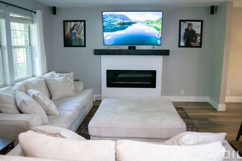A living room with a white couch and a flat screen TV mounted above a fireplace.