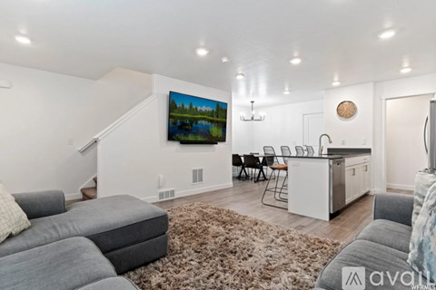 A living room with a grey couch and a television on the wall.