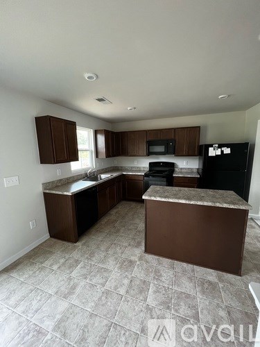 A kitchen with brown cabinets and a black refrigerator.