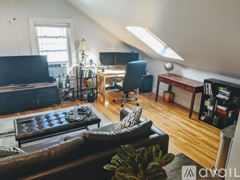 A living room with a brown leather couch and a wooden floor.
