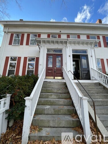 A white house with red stripes and a brown door.