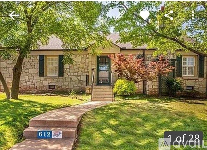 A house with a stone facade and a green lawn.