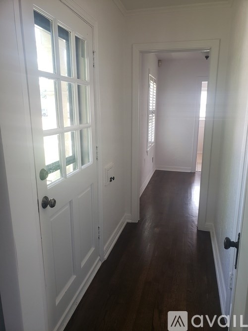 A hallway with a white door and a brown floor.