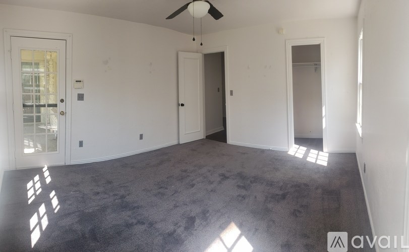 A spacious room with a ceiling fan and two doors.